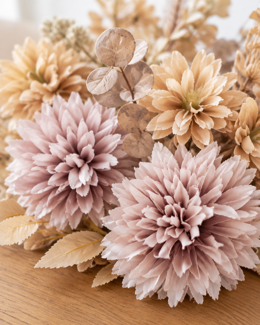 Close-up detail of the beige and mauve artificial chrysanthemum bouquet on an oak table
