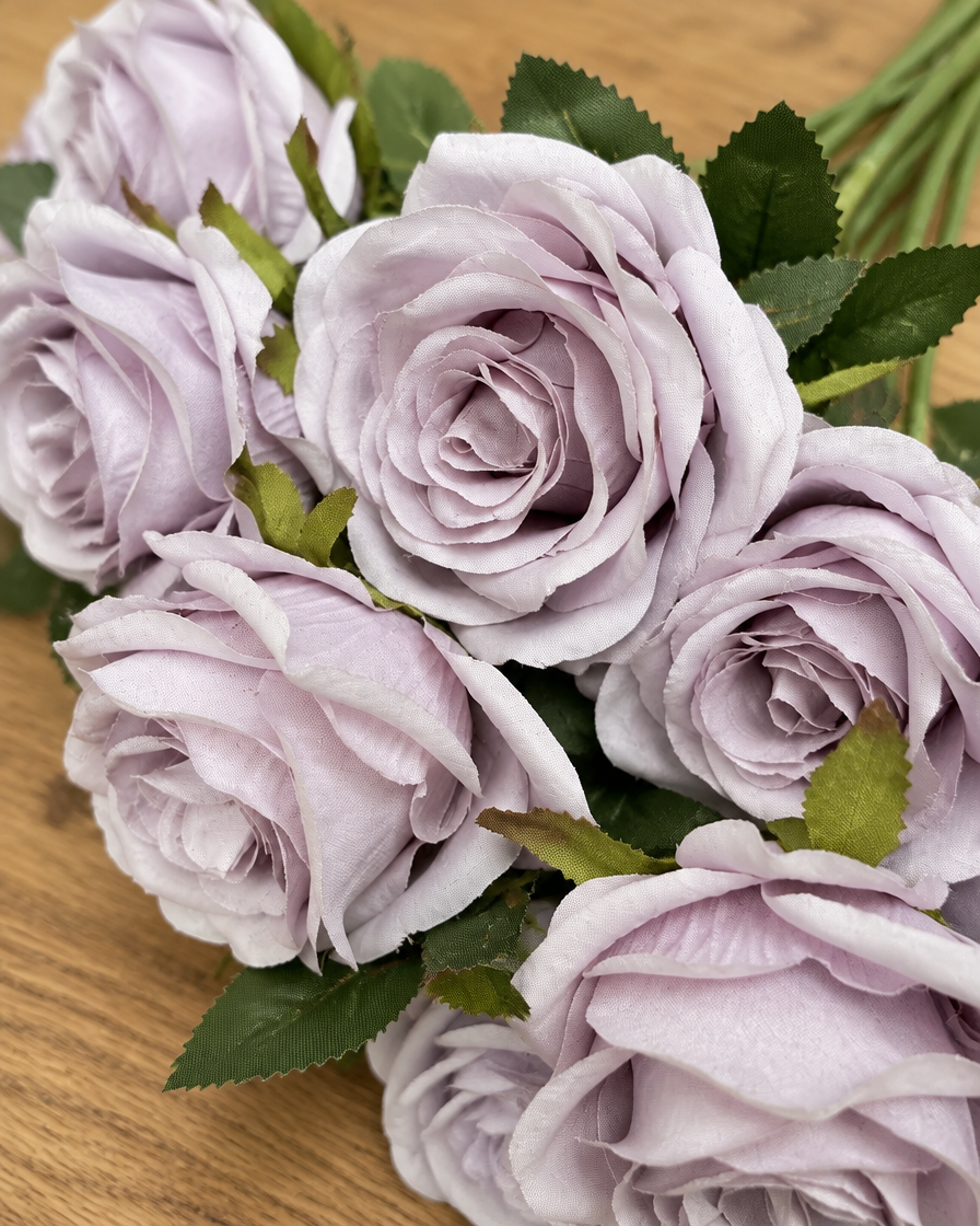 Close-up detail of the lilac artificial rose bouquet on an oak table