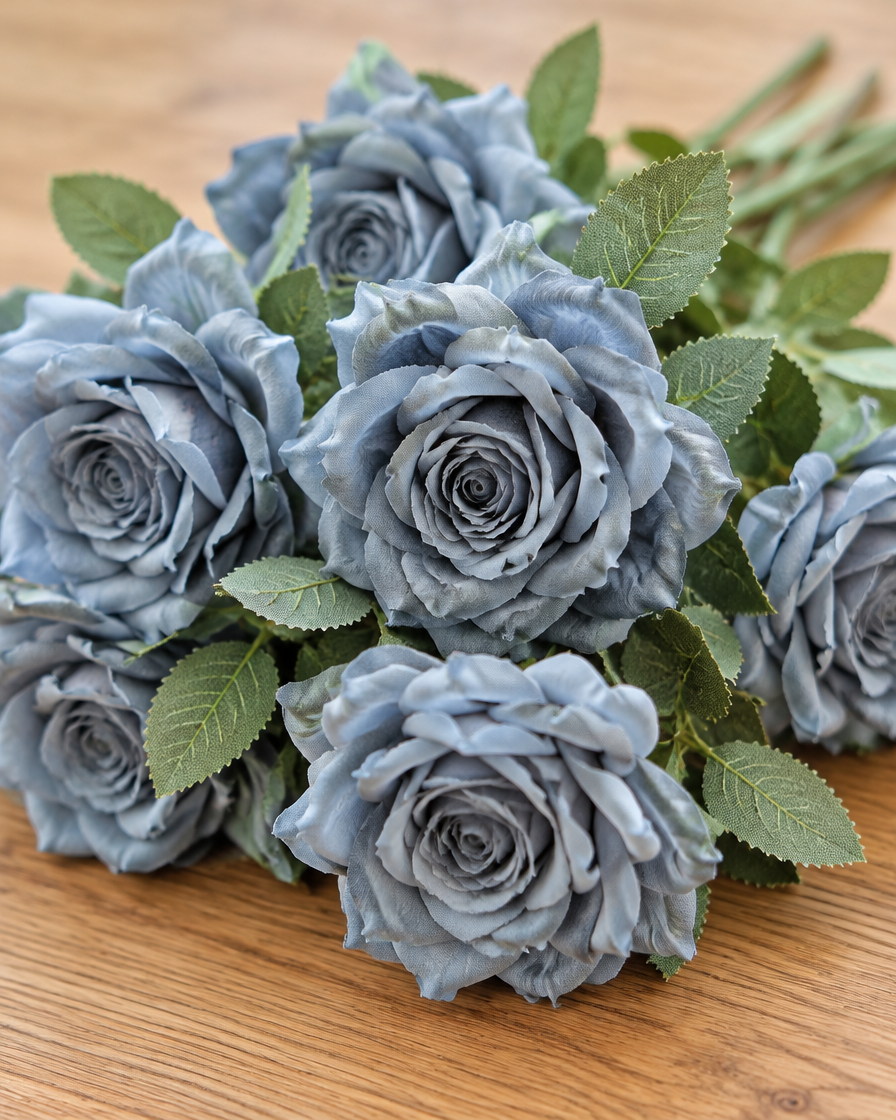 Close-up detail of the dusty blue artificial rose bouquet on an oak table