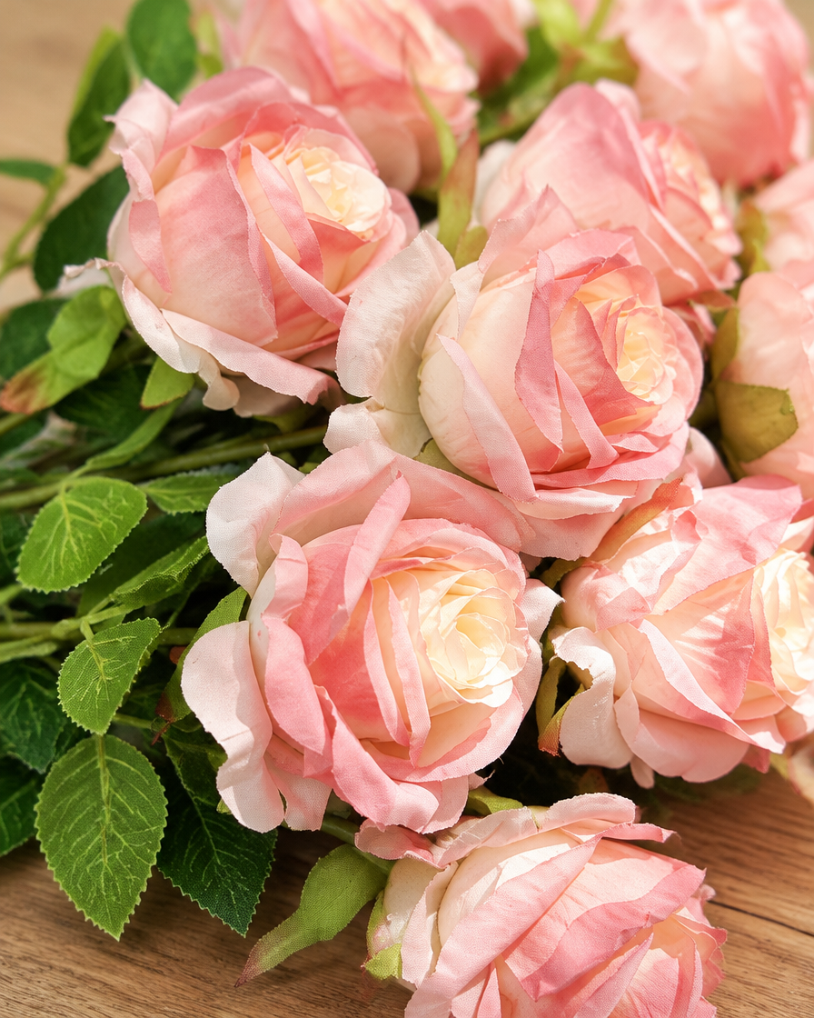 Close-up detail of the soft pink artificial rose bouquet with stems on an oak table