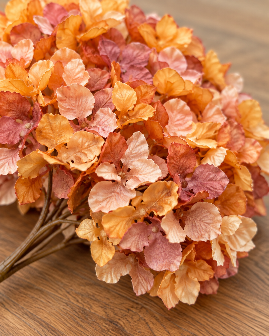 Close-up detail of the amber orange artificial hydrangea bouquet on an oak table