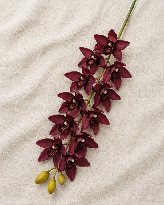 Burgundy Artificial Cymbidium Orchid Stem, shown alone on a linen background