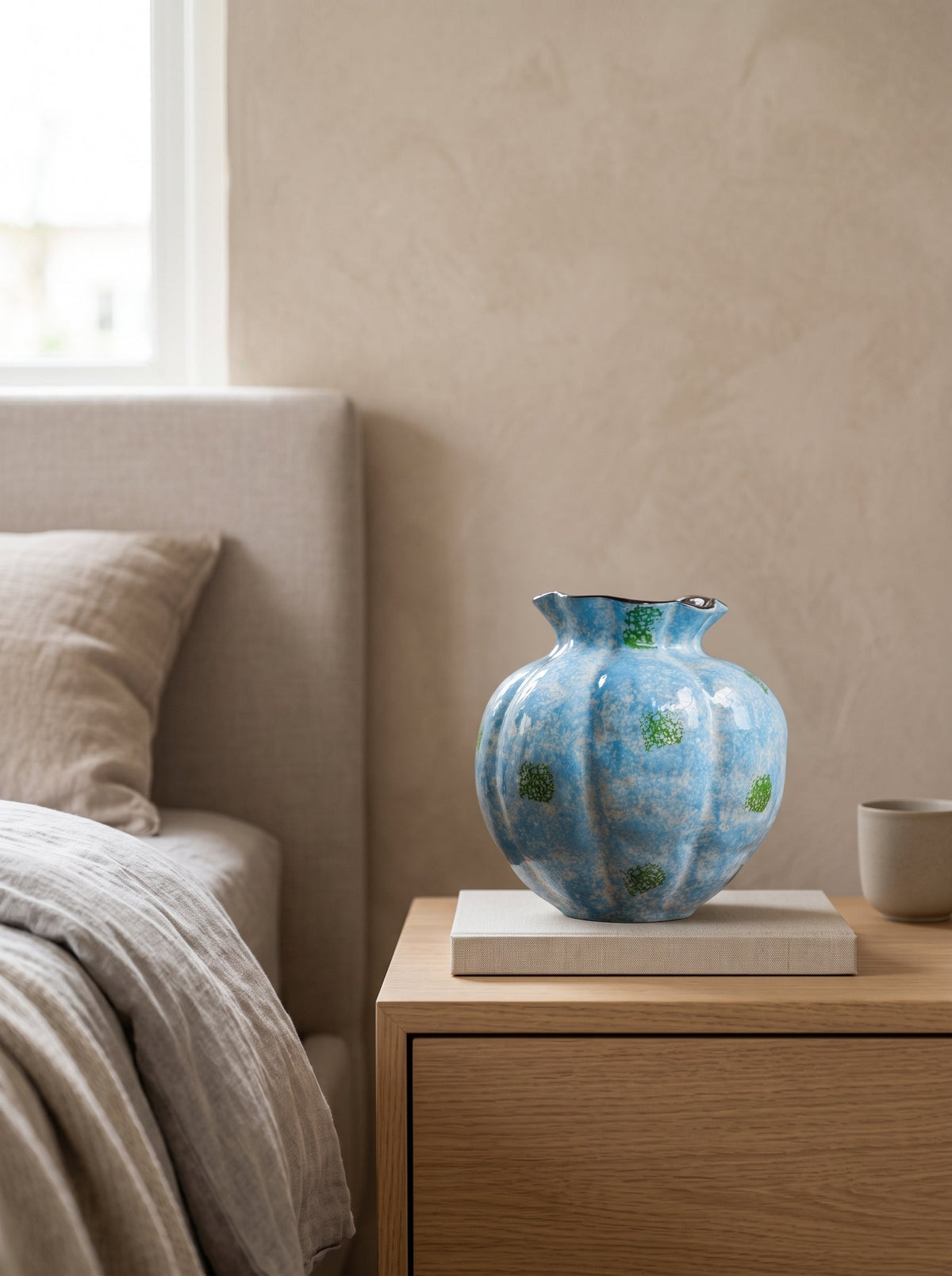 Blue speckled fluted glazed vase, empty, on a bedside table