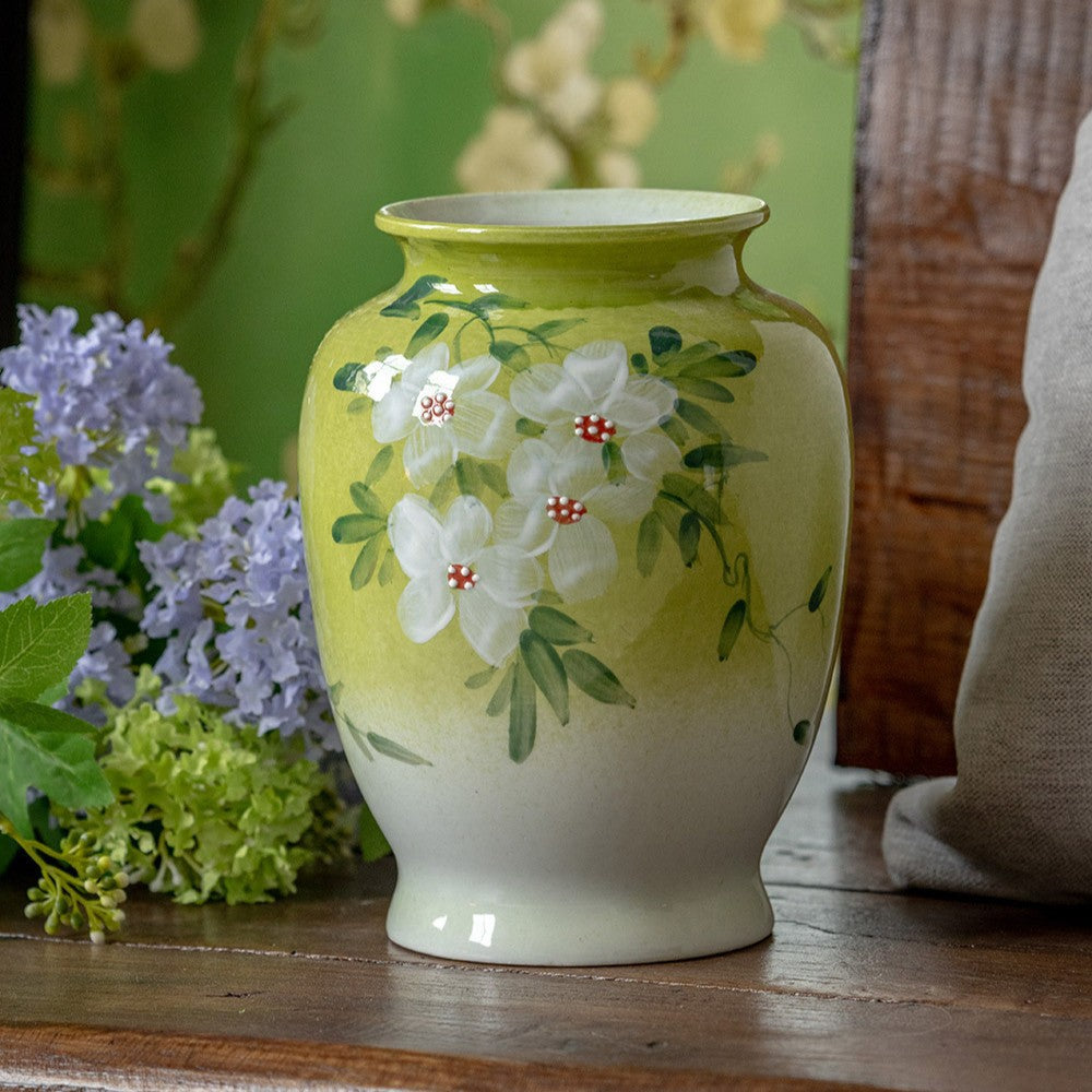 White jasmine ceramic vase in lime green and white, next to blue-purple flowers