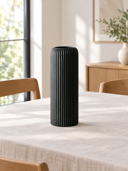 Tall matte black grooved ceramic vase on a linen-covered dining table