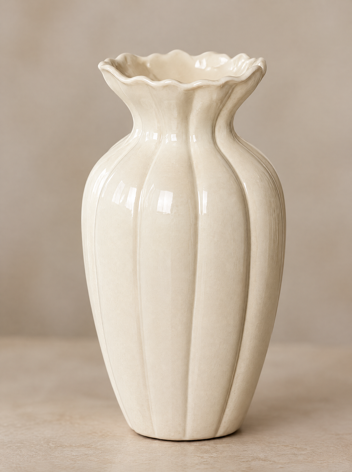 Close-up of the fluted body and wavy rim of a cream glazed ceramic vase