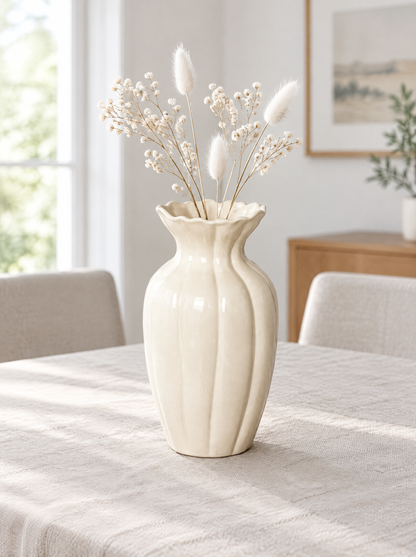 Cream fluted ceramic vase with white dried stems on a linen-covered dining table