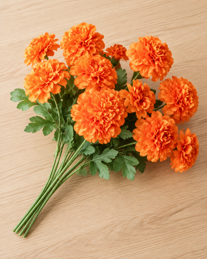 Close-up detail of the orange artificial marigold stems on an oak table