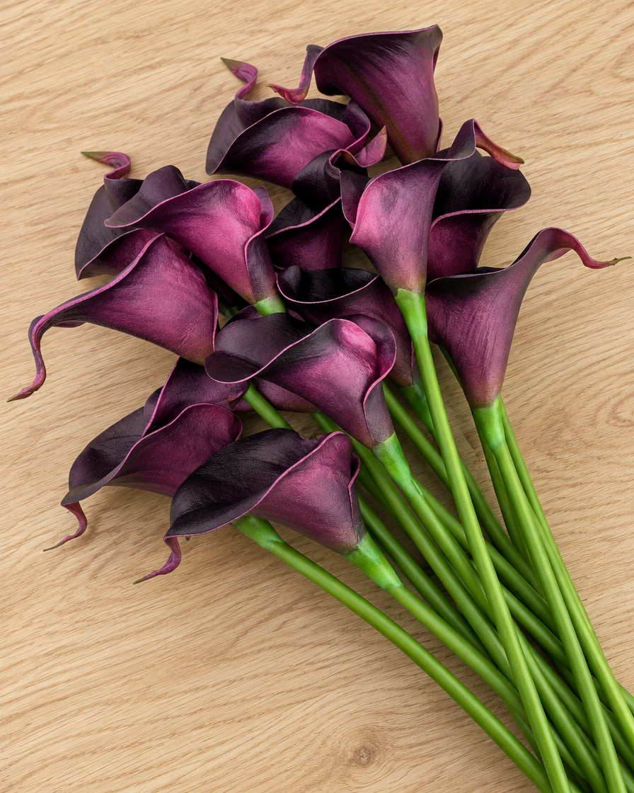Close-up detail of the dark purple artificial calla lily bouquet on an oak table