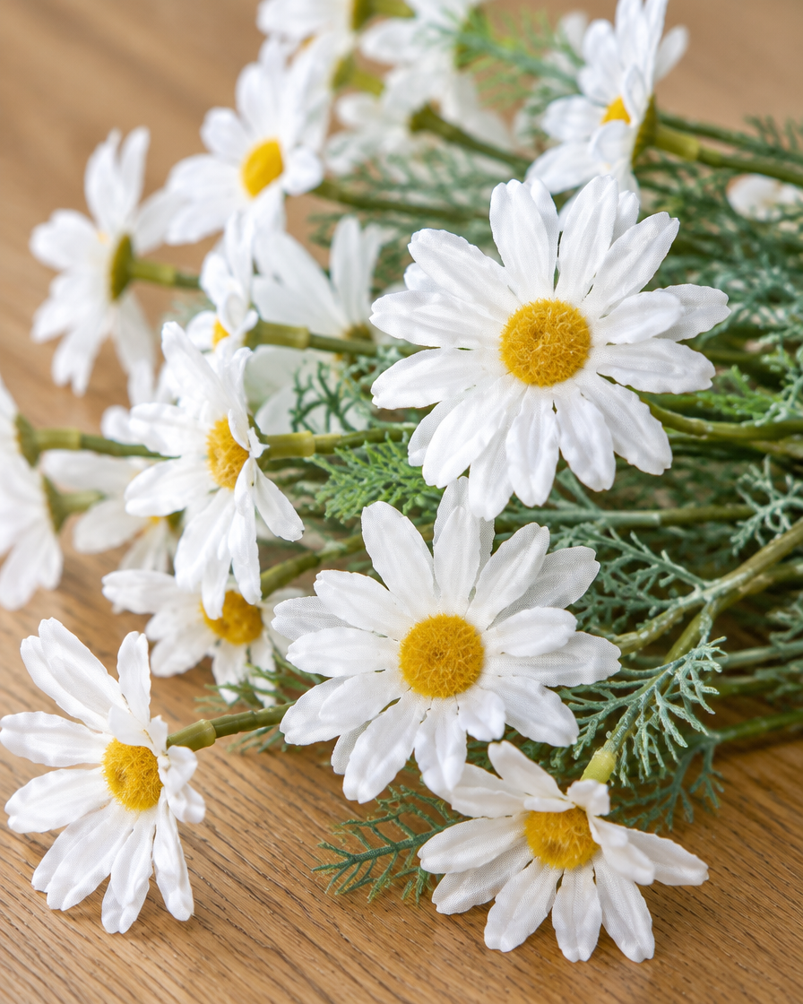 Close-up detail of the white artificial daisy bunch on an oak table