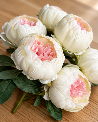 Close-up detail of the cream artificial peony bunch on an oak table
