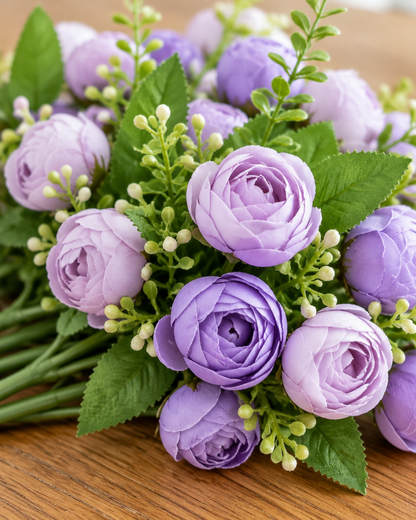 Close-up detail of the purple artificial tea rose bud bouquet on an oak table