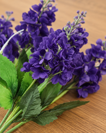 Close-up detail of the purple artificial hyacinth bunch on an oak table