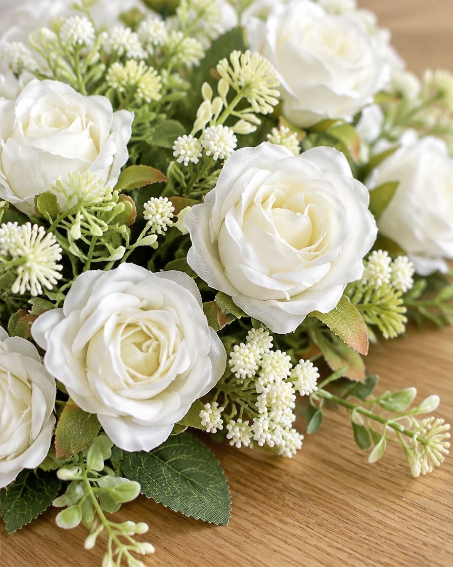 Close-up detail of the white artificial rose bouquet with greenery on an oak table