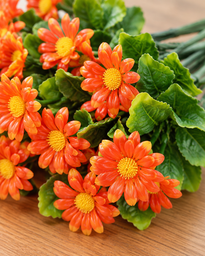 Close-up detail of the orange artificial daisy bunch on an oak table