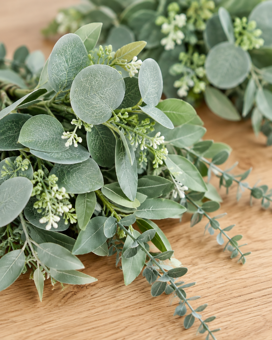 Close-up detail of the green artificial eucalyptus bunch on an oak table