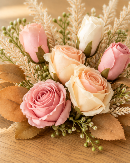 Close-up detail of the blush pink and cream artificial rose bouquet on an oak table