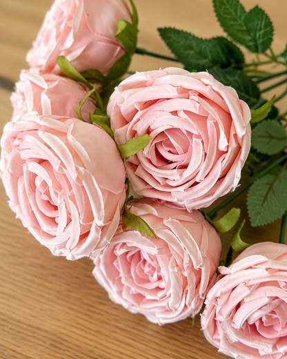 Close-up detail of the pale pink artificial rose bouquet on an oak table