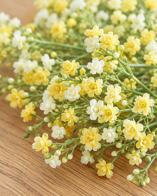 Close-up detail of the yellow artificial baby's breath bunch on an oak table