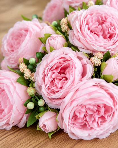 Close-up detail of the light pink artificial peony bouquet on an oak table