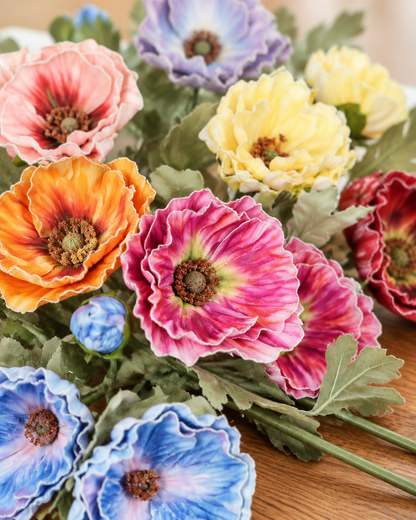 Close-up detail of the multicolour artificial poppy bouquet on an oak table