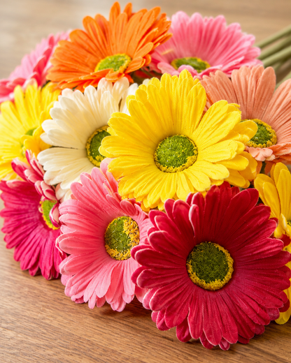 Close-up detail of the multicolour artificial gerbera daisy bunch on an oak table