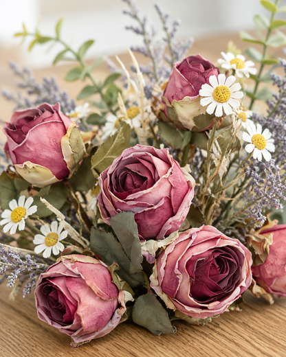 Close-up detail of the dusty mauve artificial rose and daisy bouquet on an oak table