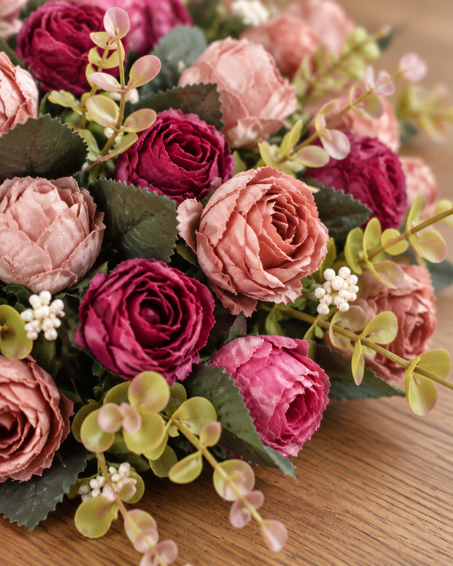 Close-up detail of the dusty pink & burgundy artificial mini rose bouquet on an oak table