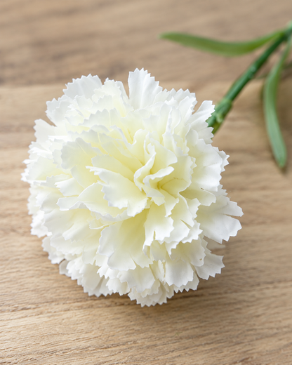 Close-up detail of the white artificial carnation stems on an oak table