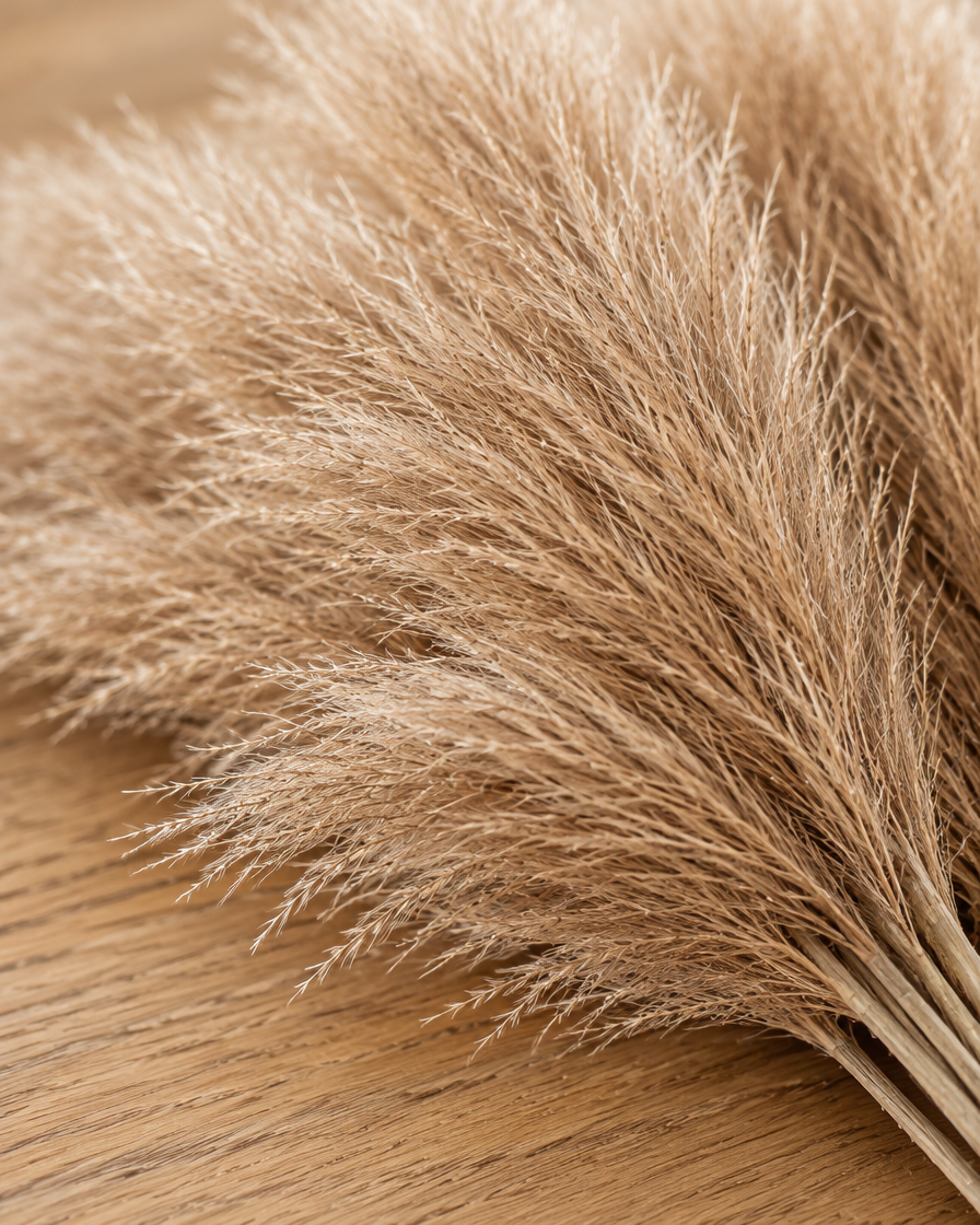 Close-up detail of the light brown artificial pampas grass stems on an oak table