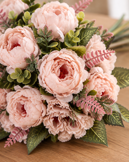 Close-up detail of the blush pink artificial peony bouquet on an oak table