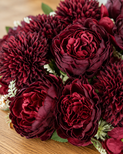 Close-up detail of the burgundy artificial peony & dahlia bouquet on an oak table