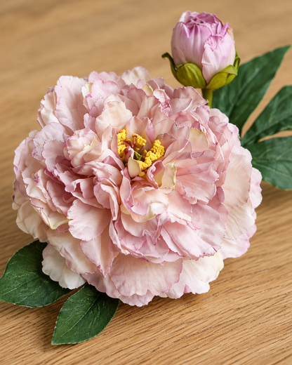 Close-up detail of the dusty lilac artificial peony stem on an oak table