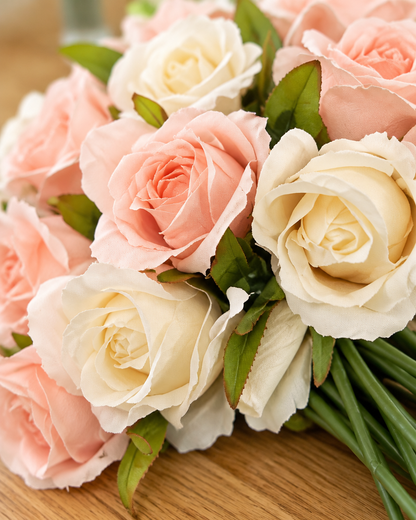 Close-up detail of the peach pink and cream artificial rose bouquet on an oak table