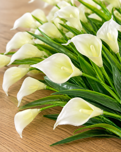 Close-up detail of the cream white artificial calla lily bunch on an oak table