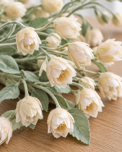 Close-up detail of the cream artificial bellflower stems on an oak table