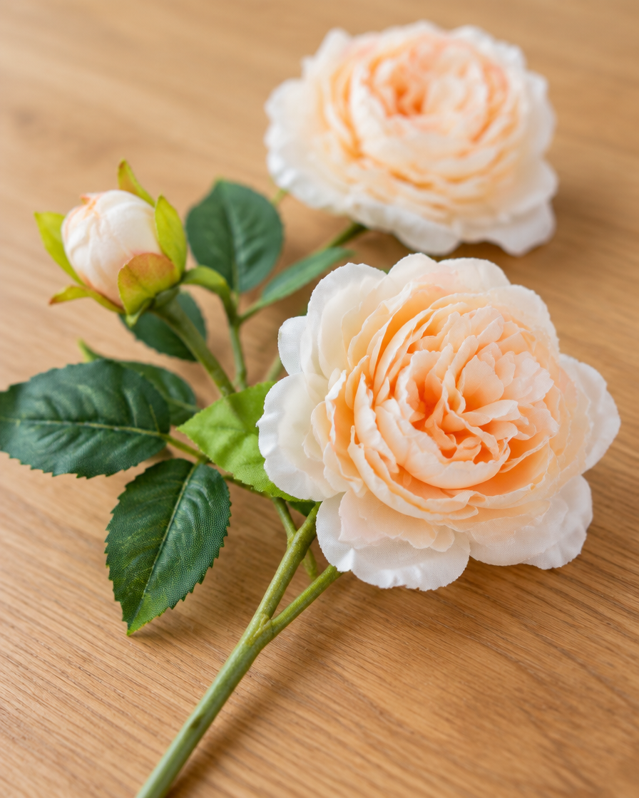 Close-up detail of the peach artificial peony stem on an oak table