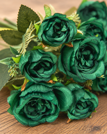 Close-up detail of the dark green artificial peony bouquet on an oak table