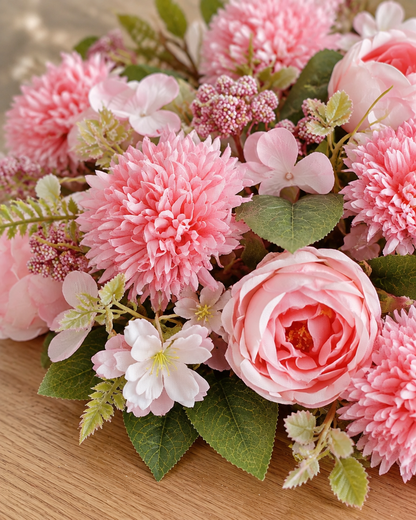 Close-up detail of the pink artificial rose & pompom mixed bouquet on an oak table