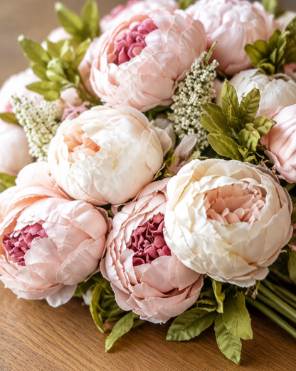 Close-up detail of the pink and cream artificial peony bouquet on an oak table