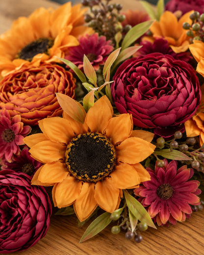 Close-up detail of the autumn artificial sunflower & peony bouquet on an oak table