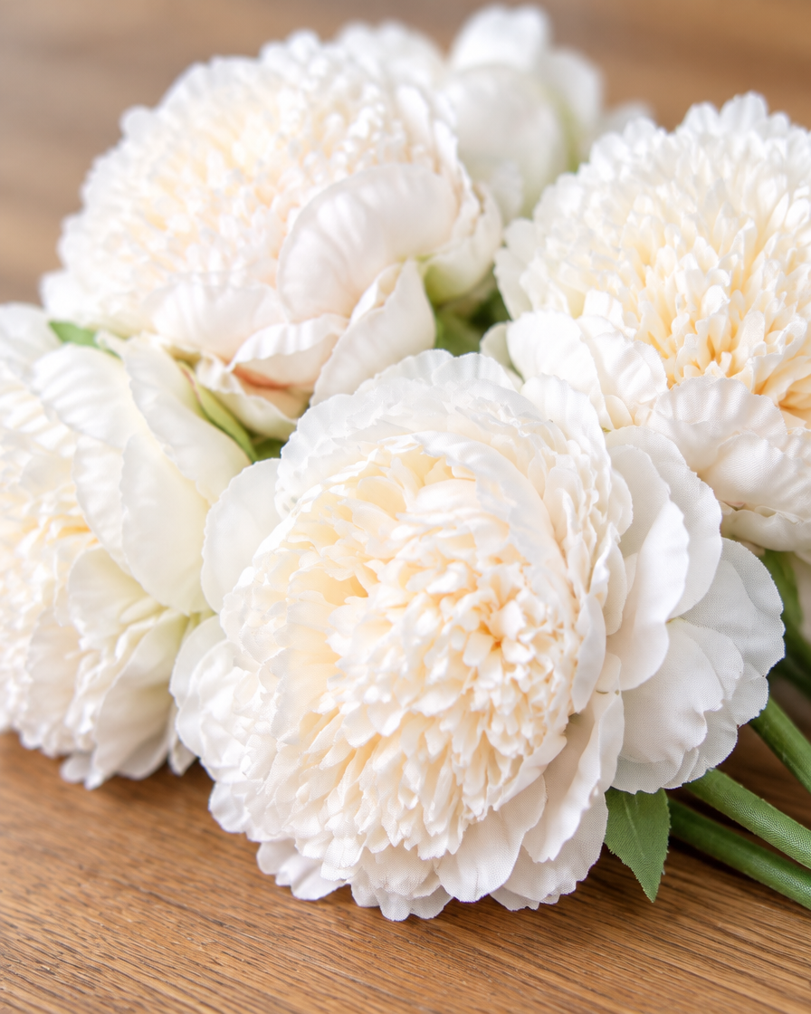 Close-up detail of the milk white artificial peony bunch on an oak table