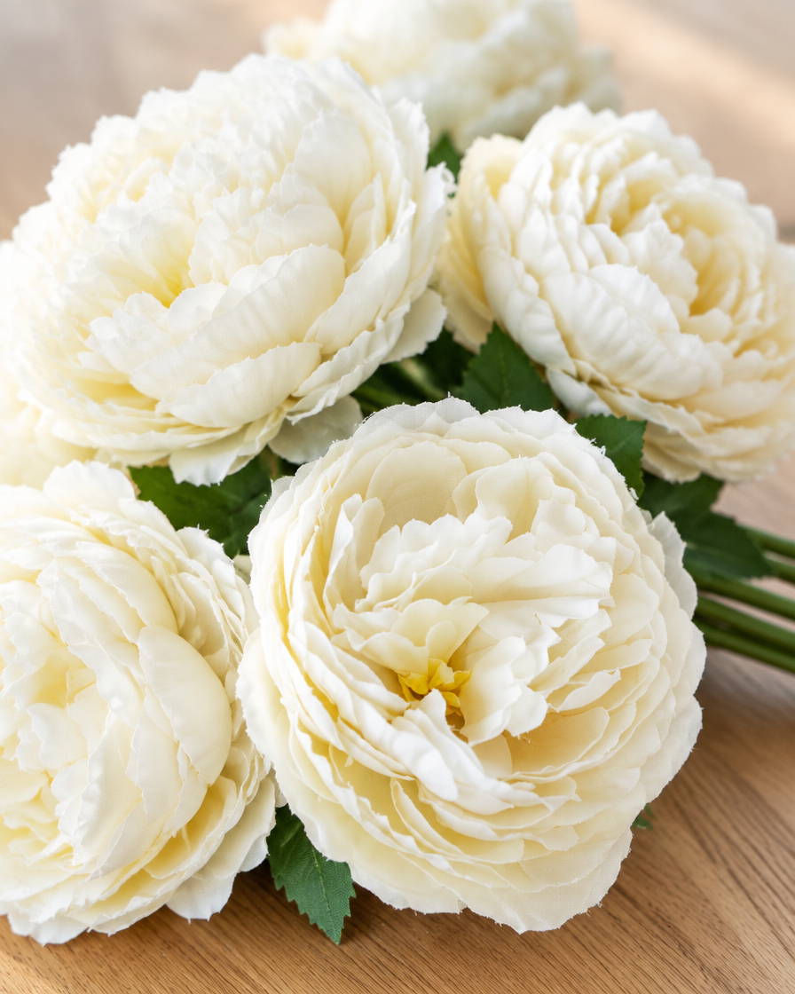 Close-up detail of the ivory artificial peony bouquet on an oak table