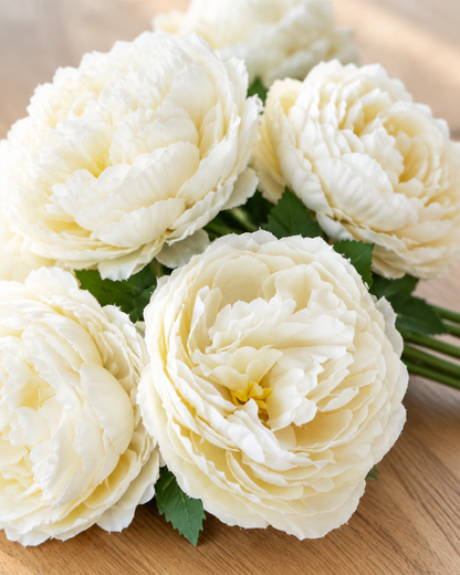 Close-up detail of the ivory artificial peony bouquet on an oak table