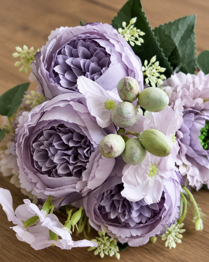 Close-up detail of the dusty purple artificial peony bouquet on an oak table