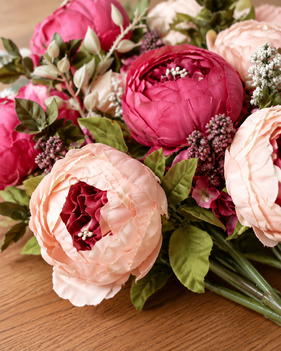 Close-up detail of the blush & rose pink artificial peony bouquet on an oak table
