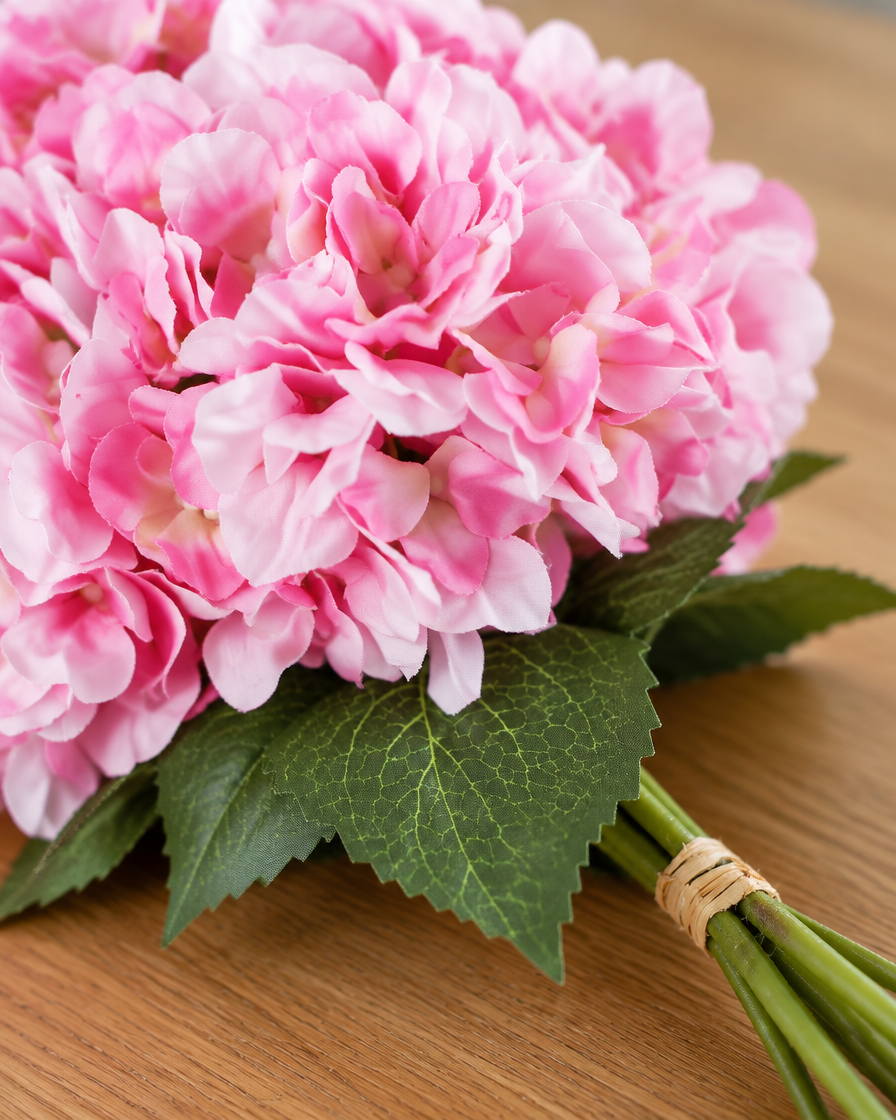Close-up detail of the pink artificial hydrangea bouquet on an oak table