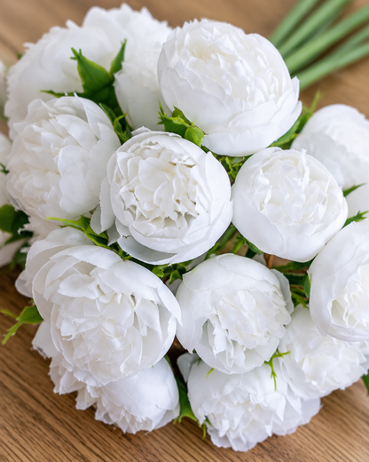 Close-up detail of the white artificial peony bunch on an oak table