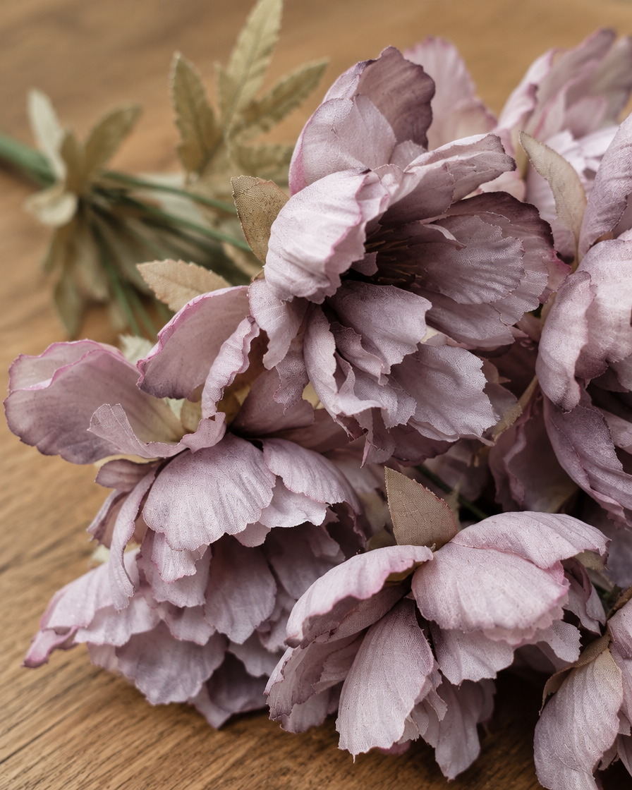 Close-up detail of the smoky mauve artificial peony bunch on an oak table
