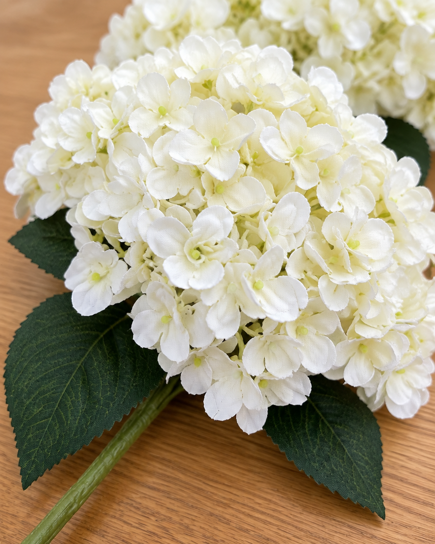 Close-up detail of the cream white artificial hydrangea bouquet on an oak table
